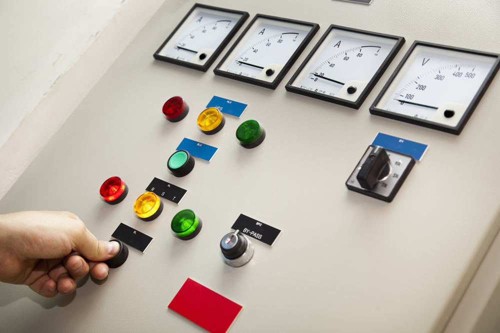 Electricity distribution controller & testing unit. An adult man's hand is pushing one of the buttons and lights up the lamps above it, apparently testing the components.